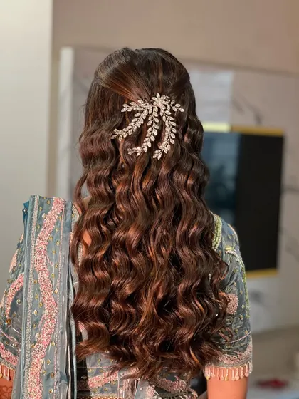 A beautiful open hairstyle with soft, romantic waves, adorned with a sparkling hair accessory for an engagement look.