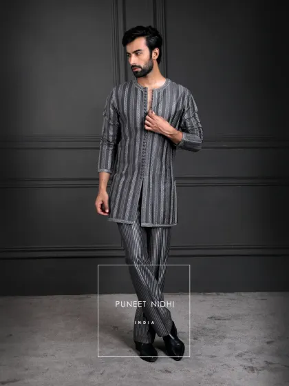 Charcoal grey geometry in motion. This kurta set features linear patterns, a lustrous texture, and a sharp straight cut, with heritage detailing in the looped buttons.