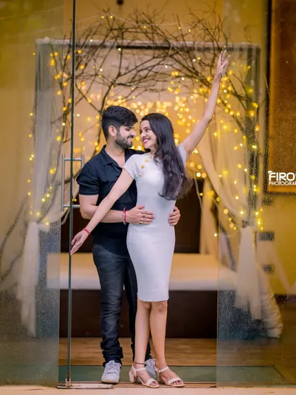 A playful, dancing pose in a beautifully lit indoor setting. The couple's casual outfits and their happy interaction make this a very lively and fun shot.