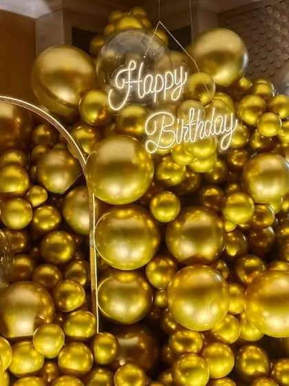 A massive installation of gold chrome balloons with a 'Happy Birthday' neon sign, creating a luxurious and high impact photo opportunity.