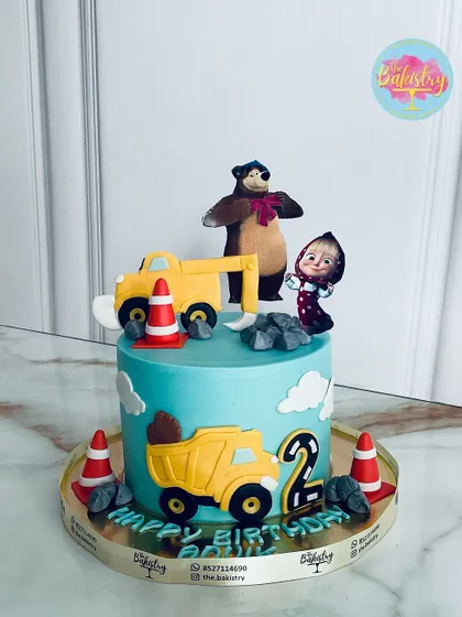 A fun and unique cake featuring Masha and the Bear at a construction site, complete with dump trucks and traffic cones for a 2nd birthday.