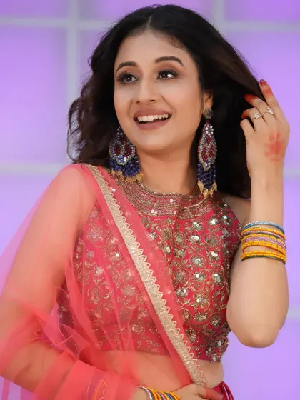 A happy, smiling shot showcasing the beautiful earrings and makeup that complement the pink lehenga.