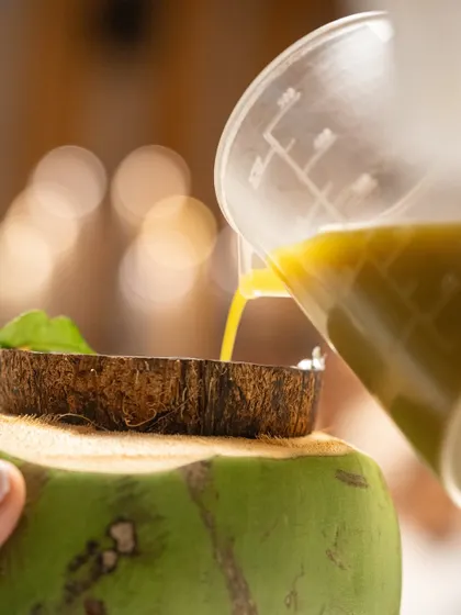 A refreshing dessert being assembled in a young coconut shell, showcasing the use of natural elements in modern plating.