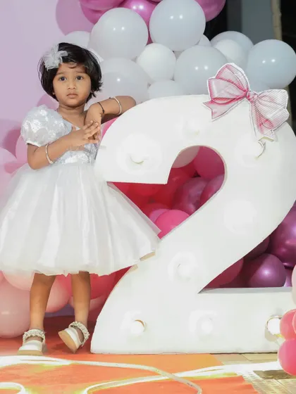 Another angle of the white one-shoulder birthday dress, showing its classic A-line shape and fluffy skirt. The design is paired with a delicate hair accessory for a complete and polished party look.