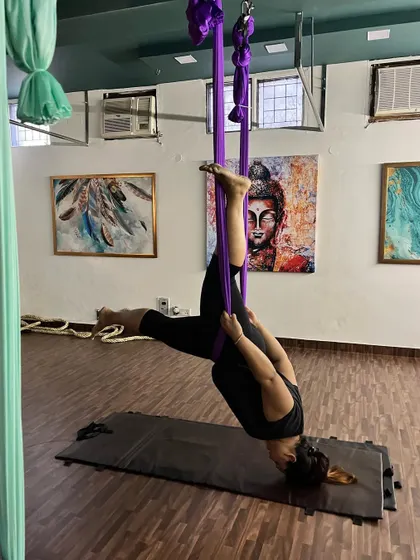 An aerial inversion in progress, showing how the silk hammock provides support around the hips to allow for a safe and deep spinal decompression. This pose is excellent for relieving back tension.