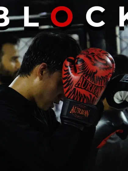 A close-up of a boxer executing a block, covering up to protect from an incoming punch. This is a fundamental defensive skill we teach in all our boxing classes.