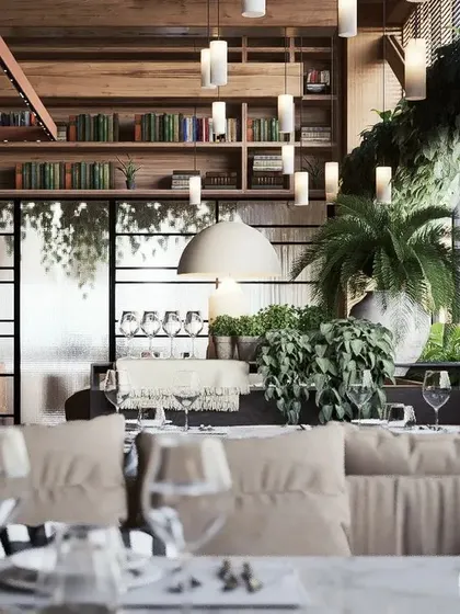 Another area of the restaurant, featuring comfortable lounge seating, a bookshelf wall, and lush plants to create a relaxed, library-like feel.