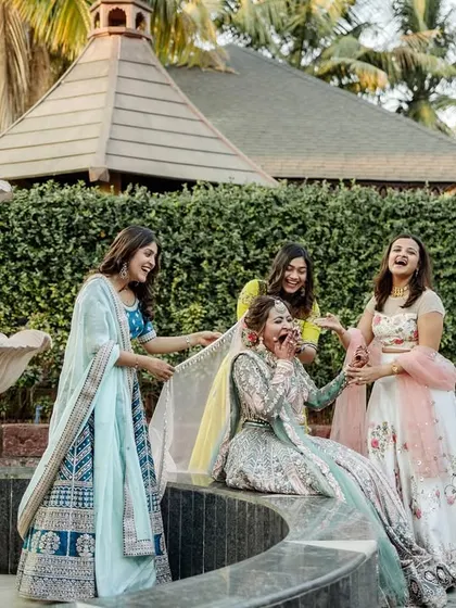 A candid, fun moment as the bride, Bhavi, shares a laugh with her bridesmaids by a fountain.
