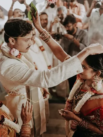 The groom performing a ritual, placing his hand on the bride's head in a moment of blessing.