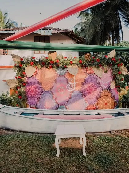 A unique photo booth for a Mehendi, featuring a repurposed boat and a colorful, artistic backdrop for guests to take pictures.