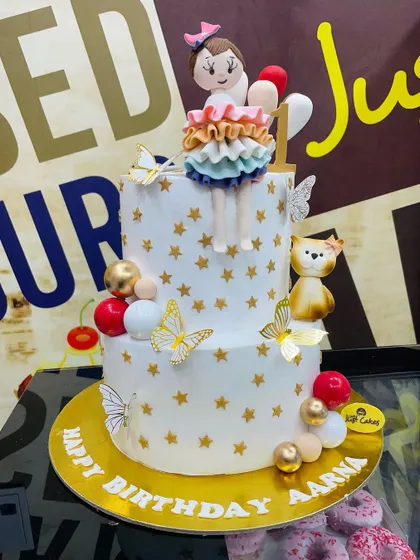 A whimsical 4kg two-tiered cake with gold stars, butterflies, and a cute girl figurine.
