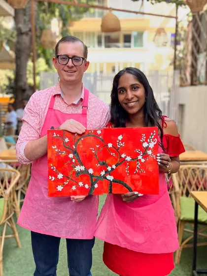 A couple holding their finished cherry blossom painting. A paint and sip session makes for a perfect and memorable date.