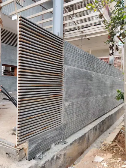 A textured concrete wall with horizontal grooves meets a metal louvered screen, an exploration of different materials and finishes.