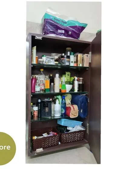 A bathroom cabinet before organizing. Toiletries and other items are stuffed onto the shelves, making it look messy.