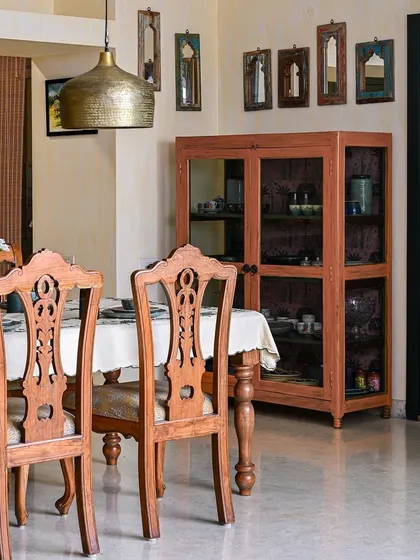 We integrated the client's cherished heirloom dining table into this space, pairing it with antique teak chairs that we repolished and reupholstered. Brass hanging lamps and distressed mirrors add to the old-world charm.