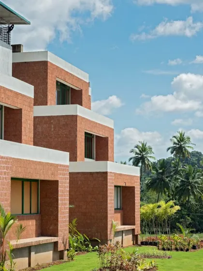 The stepped facade of the Pana Global School. The use of locally sourced laterite stone and recessed windows is a climate-responsive design strategy that also roots the building in its regional context.