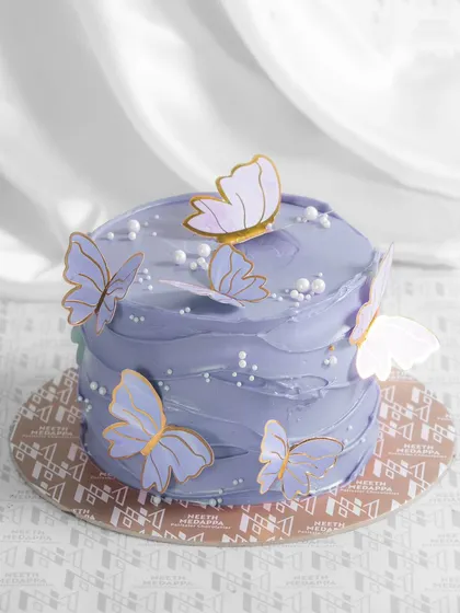 A lovely purple butterfly cake, with delicate butterflies that seem to float on the soft, textured frosting.