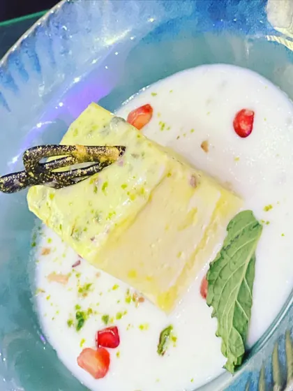 A modern take on a classic Indian dessert. This plated Pista Kulfi is served in a creamy rabri with fresh mint and pomegranate, offering a refreshing and elegant end to a meal.