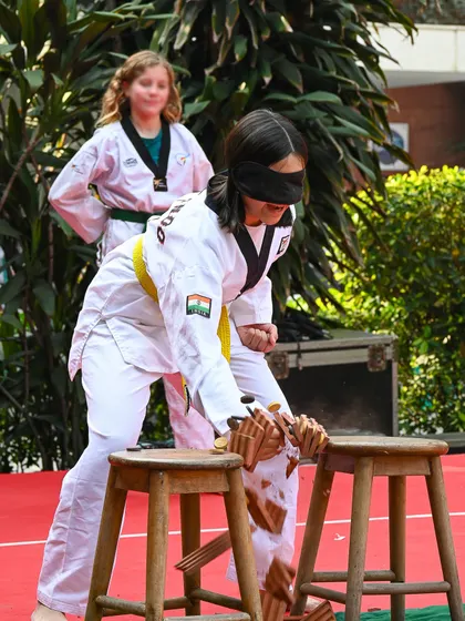 A student in a Taekwondo uniform breaks boards blindfolded. Our events often feature impressive demonstrations of skill from students and community members.