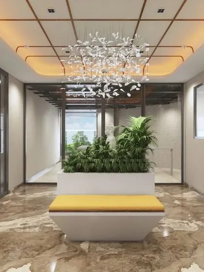 A view down the corridor at the Mahalakshmi Logistics office, highlighting the custom ceiling with warm backlighting and a modern chandelier. The design uses lighting and materials to guide movement through the space.