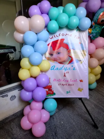 A personalized welcome sign for a Cocomelon-themed first birthday party, framed with a colorful pastel balloon garland.