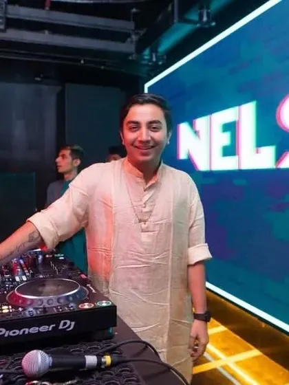 Standing by my decks with my logo on the big screen. This is my stage, where I bring my brand of high-energy music to life.