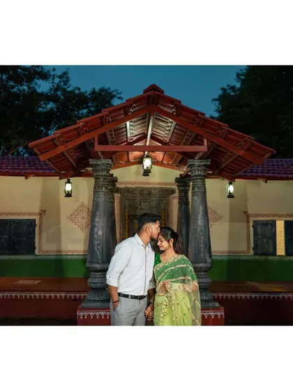 A quiet evening moment during a pre-wedding shoot. The groom's gentle kiss on the forehead captures the tenderness of their relationship.