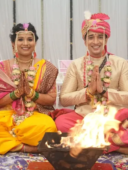 A couple seated before the sacred fire (homa) during their wedding ceremony, joining their hands in prayer.