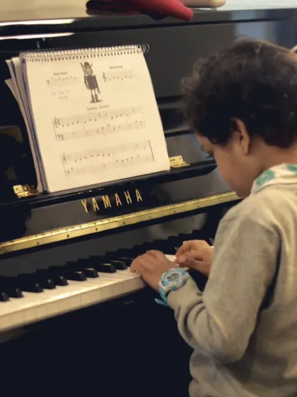 A young student carefully reading his music while playing the piano. We focus on building strong foundational skills in music theory and sight-reading.