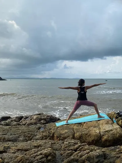 A student in Virabhadrasana II (Warrior II) against a stunning beach sunset. This powerful image shows the strength and grace that a consistent practice builds.