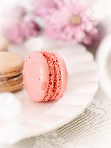 A tight shot of a single pink macaron, perfect for highlighting a specific flavor or product.