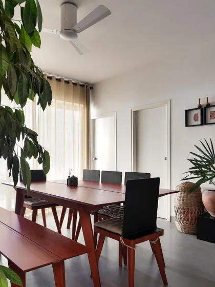 The dining space in 'Rustic Minimal' is filled with greenery. We use plants of various sizes to add life and a tropical feel, making the apartment feel like an urban oasis.