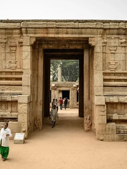 The entrance to a temple in Hampi, capturing daily life as people walk through the ancient gateway.