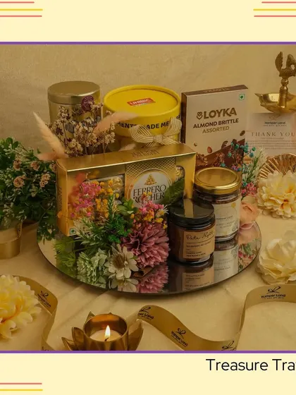 The "Treasure Tray" is a stunning centerpiece gift. A mirrored tray holds Ferrero Rocher, gourmet snacks, and a candle, all surrounded by floral decorations.