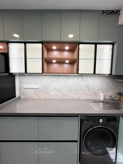 Here, we used a combination of clear and fluted glass on the overhead cabinets, separated by an illuminated wooden display niche. This mix of materials adds visual interest and personality to the kitchen.