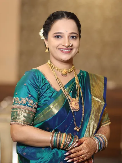 A smiling portrait showing her complete look with traditional gold jewellery.