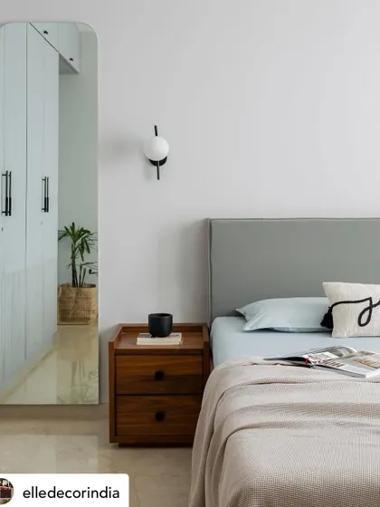 This serene bedroom detail from 'House Nandini' was highlighted in our Elle Decor feature. The minimalist aesthetic, with its clean lines, soft grey headboard, and simple wooden nightstand, creates a calming atmosphere.