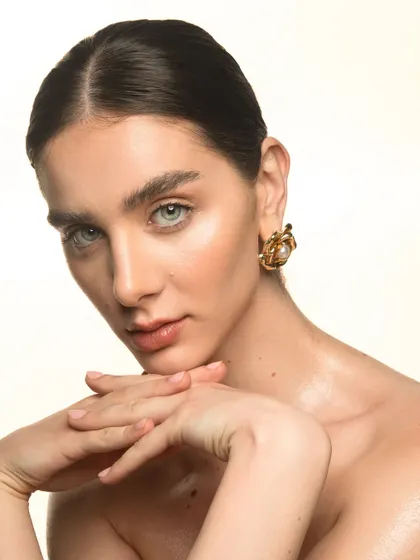 A soft, elegant portrait. The makeup is minimal and timeless, with glowing skin, brushed-up brows, and a hint of color on the lips.