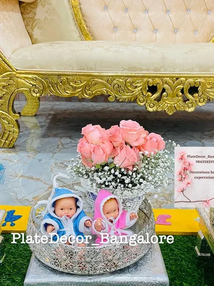 This arrangement for a twin baby shower includes a basket of fresh pink roses and two baby dolls. It’s a sweet and elegant way to present gifts for the mother-to-be.