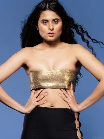 A close-up of a model in a gold bandeau top, with a confident and direct gaze.