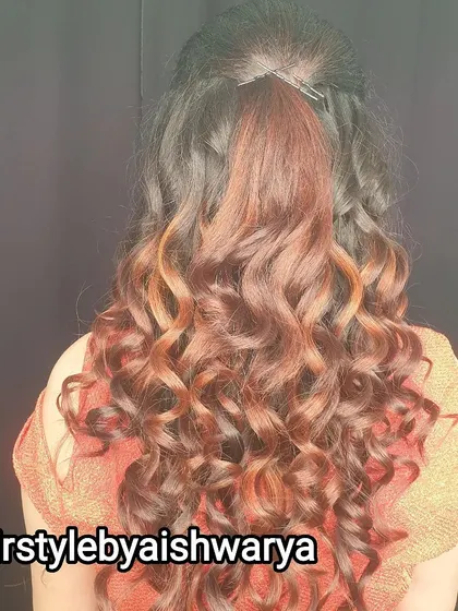 Beautifully defined curls with subtle highlights. This simple half-ponytail style is perfect for showcasing hair color and texture.