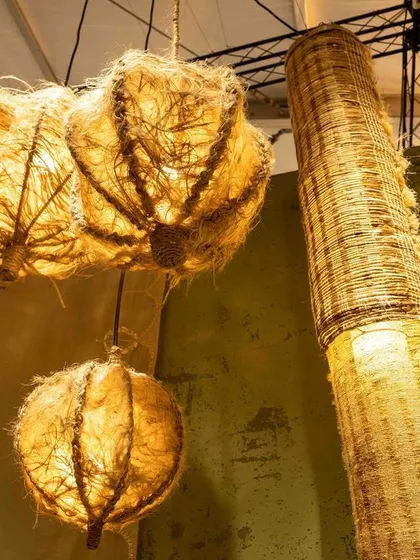 A detail of the lighting within the 'Edge of the Forest' installation. The woven pendants, made from natural fibers, cast a warm, dappled light that enhances the feeling of being in a serene, healing space away from the urban jungle.