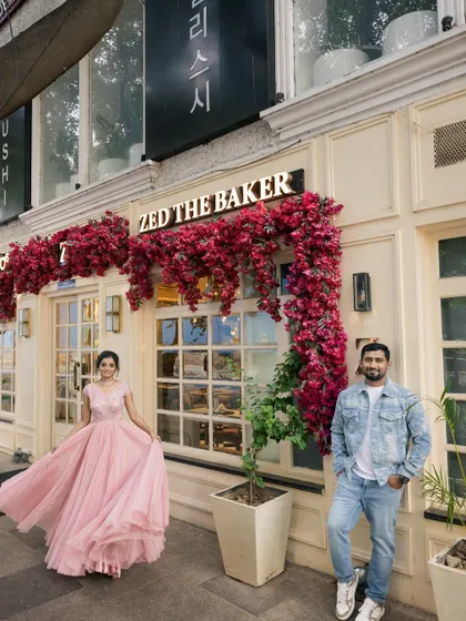 A playful and romantic pre-wedding photo in front of a charming bakery, with the bride's dress in motion.