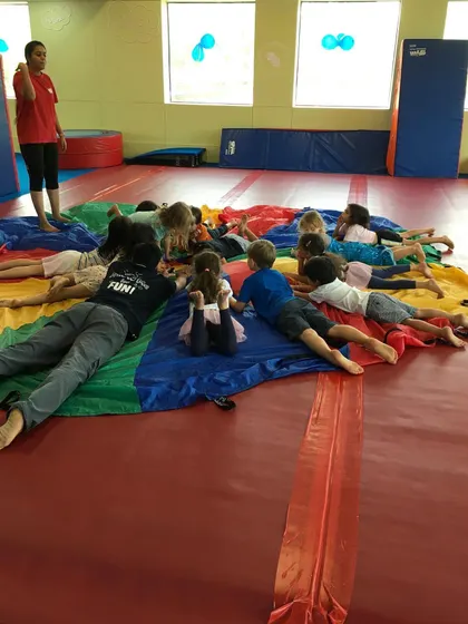 Time for a cool-down. After high-energy games, our instructors lead the children in a relaxing activity on the parachute.
