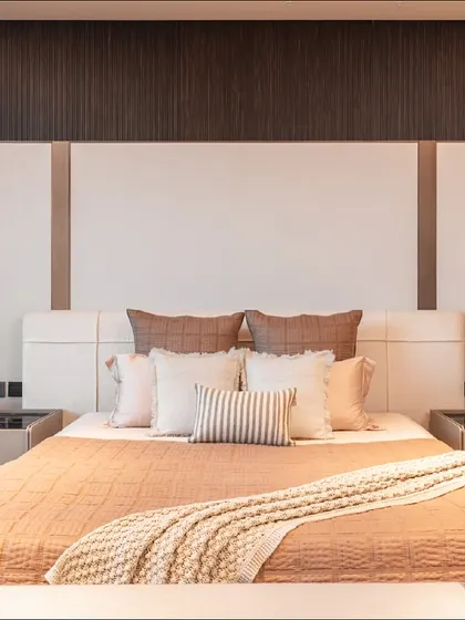 In this Gurugram bedroom, a captivating wallpaper screen is paired with fluted veneer paneling to create a striking backdrop for the bed. The design ensures an open and free-flowing space, with custom nightstands and shelving providing both style and function.