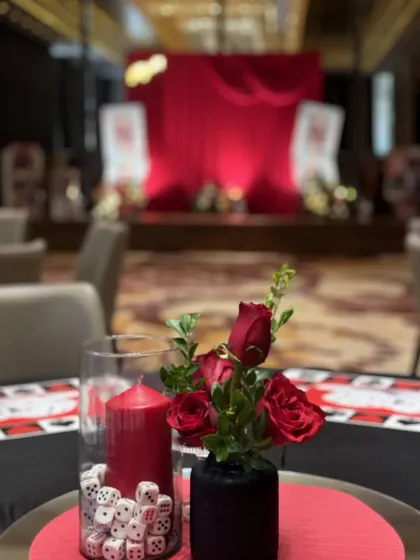 Another perspective of the casino night setup, with a focus on the themed table decor, including dice-filled vases and red roses, set against the backdrop of the main stage.