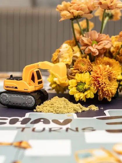 A close-up of the personalized placemat and a toy excavator with edible sand, a detail that delighted the younger guests.