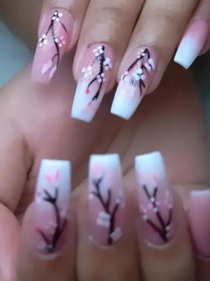 These square-tipped extensions feature a pink-to-white ombre base, enhanced with delicate cherry blossom branch nail art.