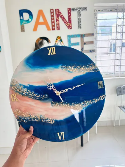 A resin clock with a unique pink and blue wave design, accented with gold flakes.