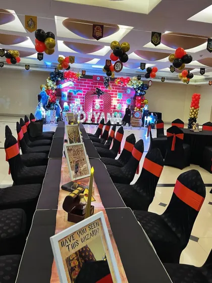 The Great Hall dining setup, with long tables, house-colored chair sashes, and a Marauder's Map-style table runner.